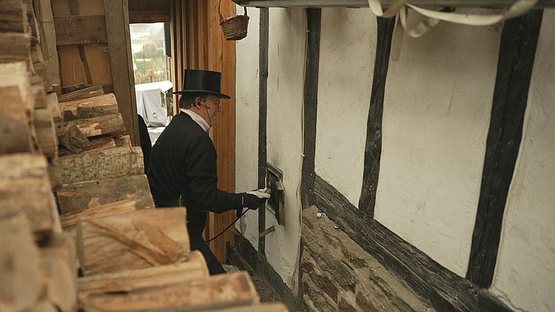Paul-Werner Giebeler is bezig met het van buitenaf schoonmaken van een schoorsteen