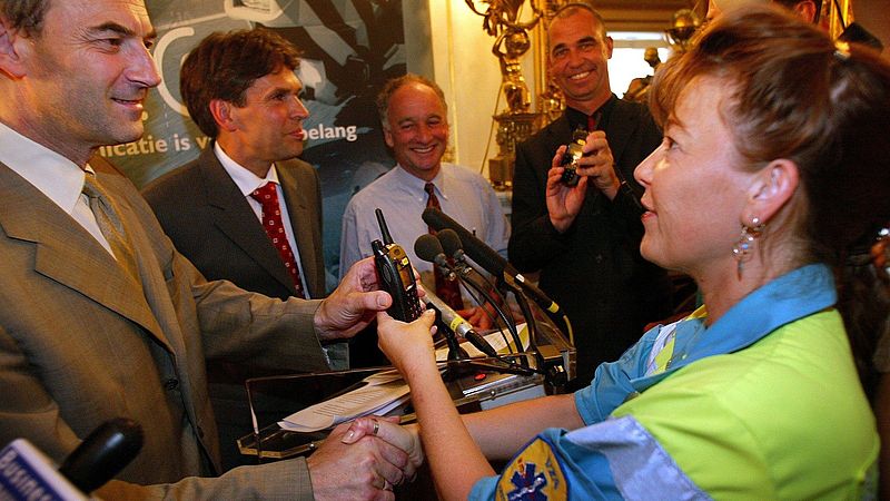 Toenmalig burgemeester van Amsterdam Job Cohen overhandigt c2000-portofoon